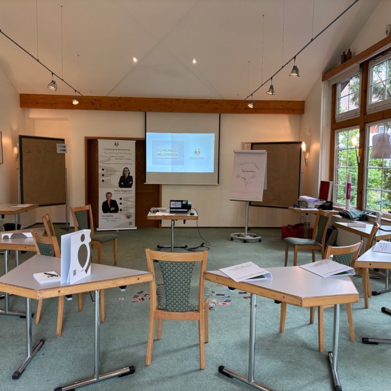 Erkenntnispfade Seminarraum mit Tischen, Stühlen und einer Präsentation auf einer Leinwand.